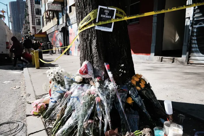 Mourners leave flowers at the base of a tree stump outside the Chinatown apartment building where Christina Yuna Lee was killed on Feb. 13, 2022.